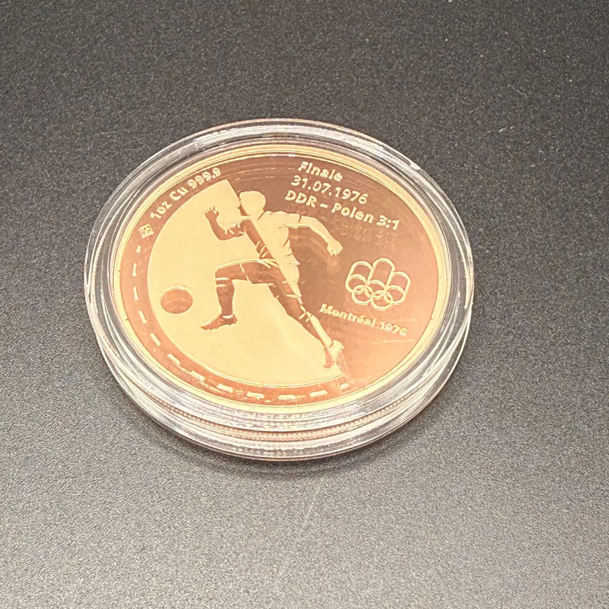 Fotografie der Medaille in ihrer Schutzkapsel, Vorderseite, auf dunklem Grund